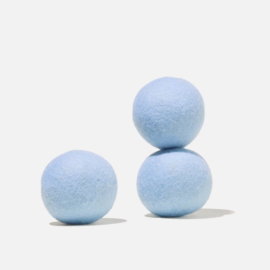 Three light blue wool dryer balls, with two stacked on top of each other and one resting beside them, on a plain white background.