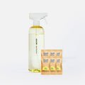 A clear spray bottle labeled Blueland Multi-Surface stands next to six small yellow and orange Blueland cleaning tablets in paper packets, all set against a white background.