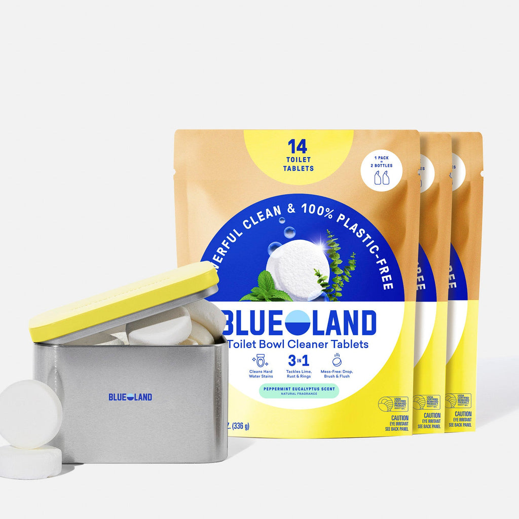 A lavender tin labeled Blueland Toilet Cleaner with white cleaning tablets inside is in front of three yellow and blue refill pouches labeled Blueland Toilet Bowl Cleaner Tablets – 14 count, 3-in-1, Peppermint Eucalyptus Scent.