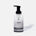 A clear glass soap dispenser with a black pump top and the word BLUELAND printed on the front, shown against a plain white background.